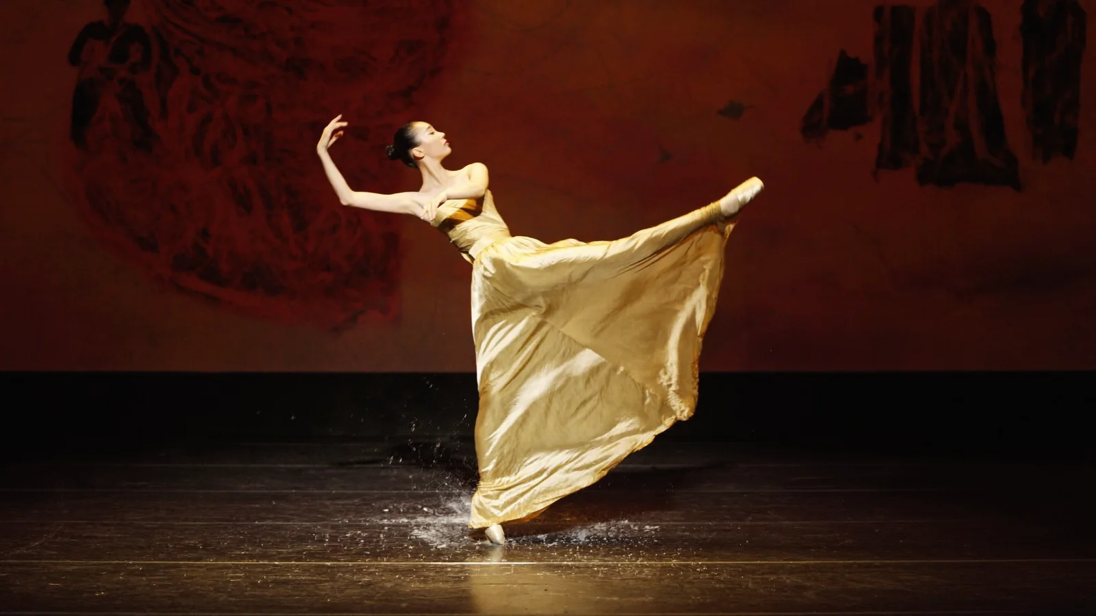 Illustrative image of a ballet dancer mid-leap on a dramatically lit stage with flowing silk fabric evoking Dunhuang mural art, not a photo from the production