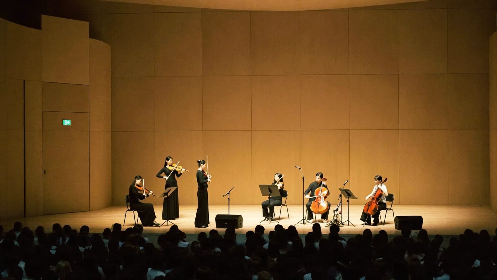 Illustrative image of a string quartet performing on a concert hall stage before a seated audience, representing the HK Phil community concert