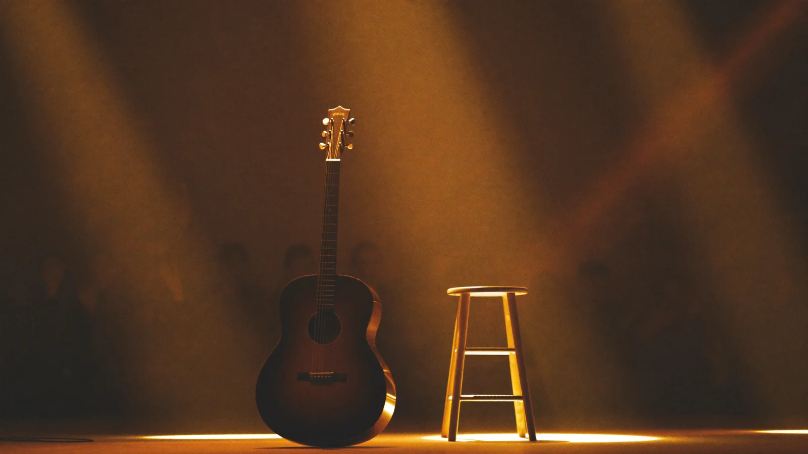 Illustrative image of a solo singer with an acoustic guitar under a warm spotlight on an arena stage