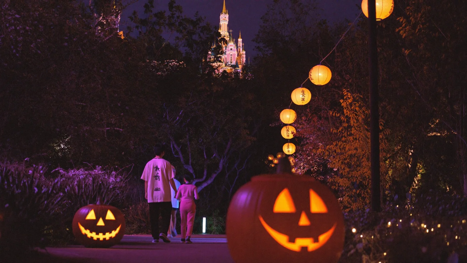 Illustrative image of glowing jack-o'-lanterns along a theme park path at night
